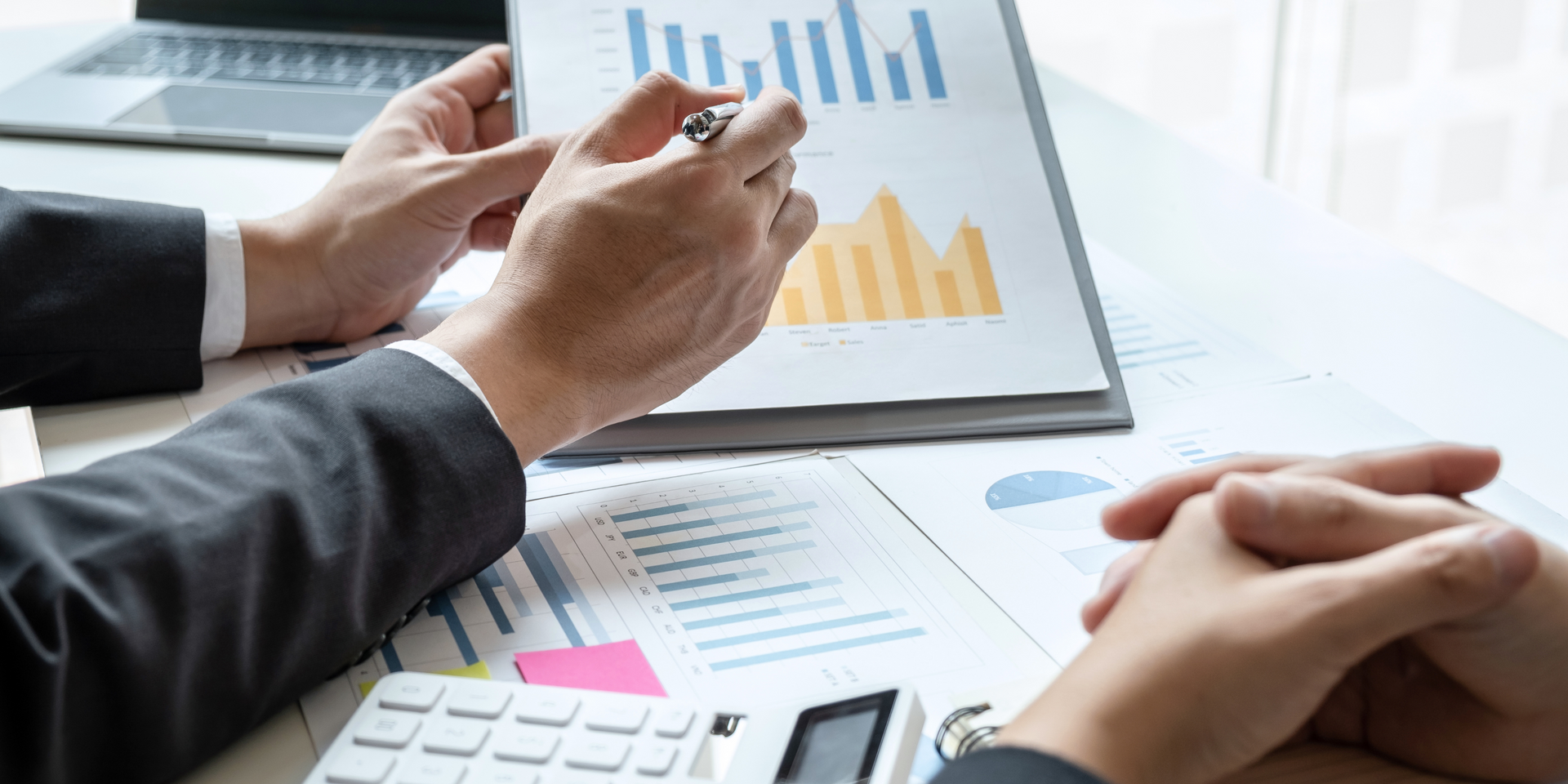 A pair of hands on a table looking at data and graphs