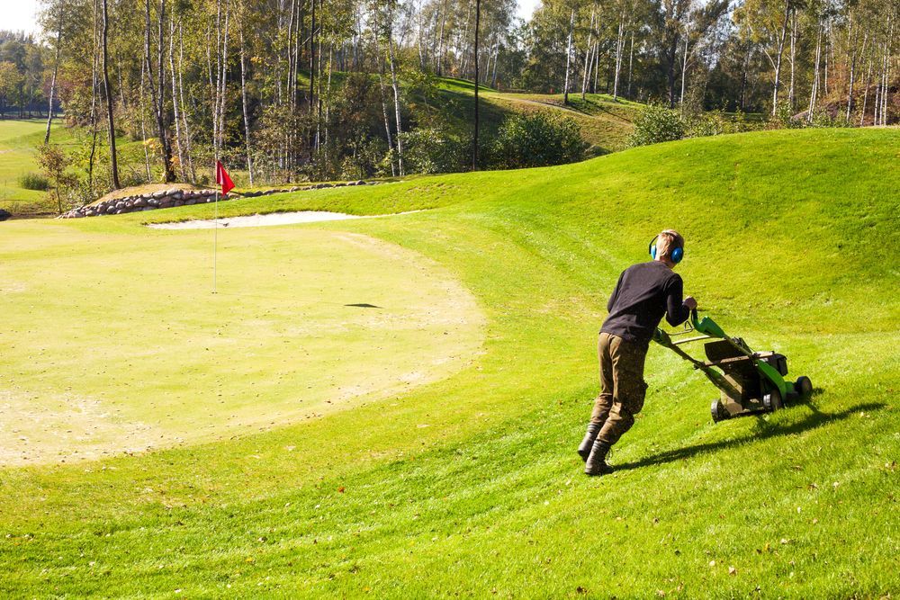 A horticulture labourer mowing a golf course