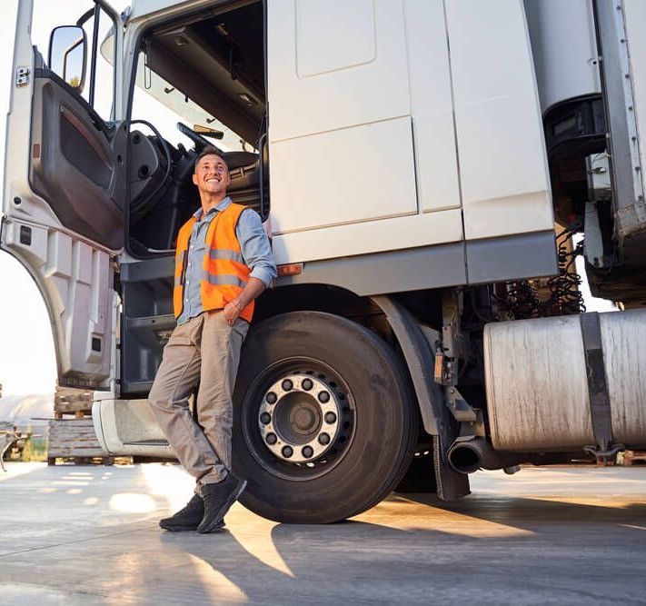 A man wearing orange hi-vis leaning against a truck