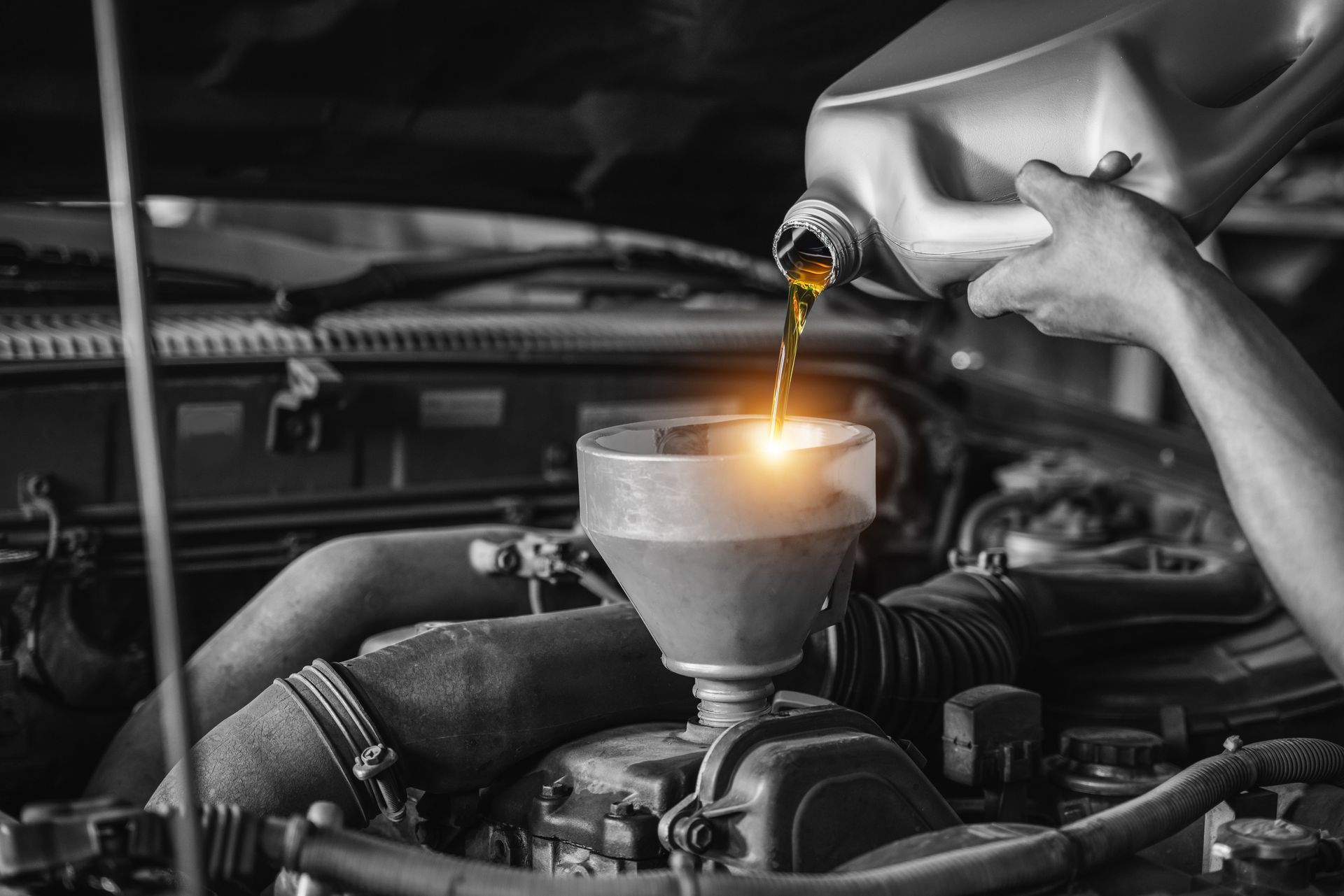 Person pouring oil into a car engine with a funnel. Person pouring oil into a car engine with a funnel.