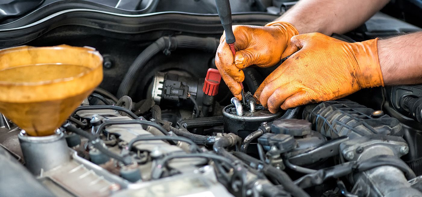 Mechanic’s orange-gloved hands repairing car engine components in a garage