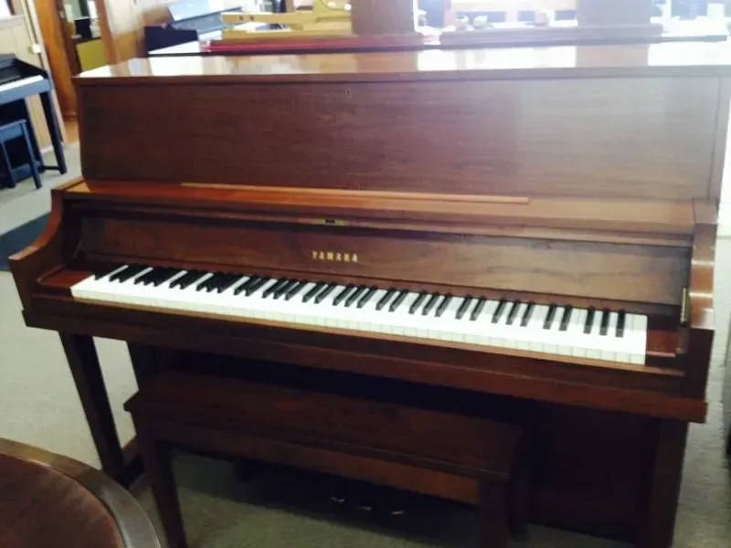 A yamaha piano is sitting on the floor in a room