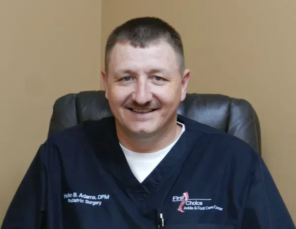 A smiling doctor in a lab coat with a stethoscope around his neck.
