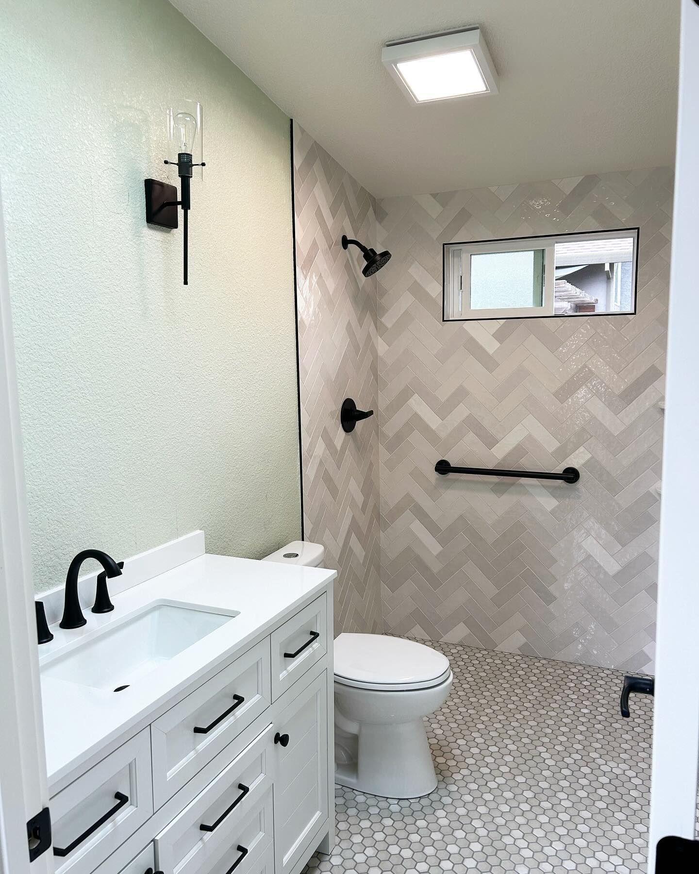 Accessible bathroom with white vanity, walk-in shower, toilet, and tiled floor and walls.