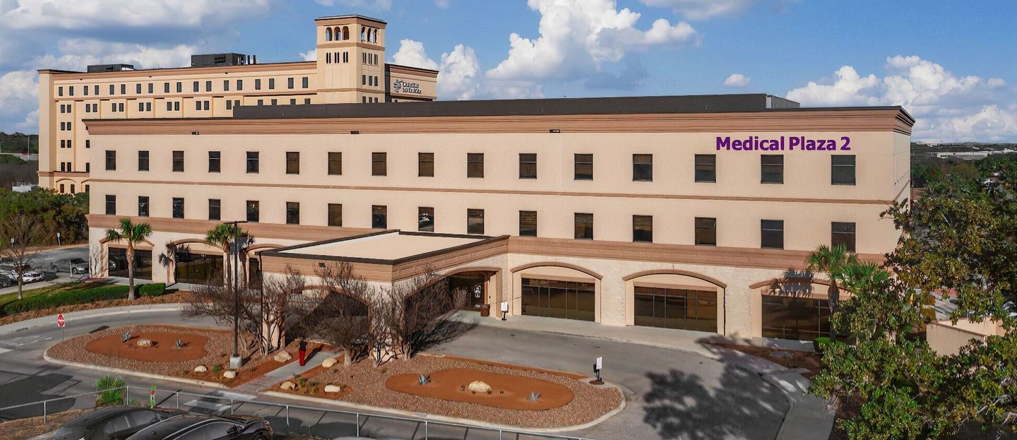 Hospital building with a covered entrance, labeled “Medical Plaza 2,” under a blue sky