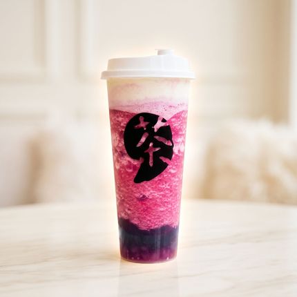 Pink blended drink in a clear cup with a white lid and black logo on a light table
