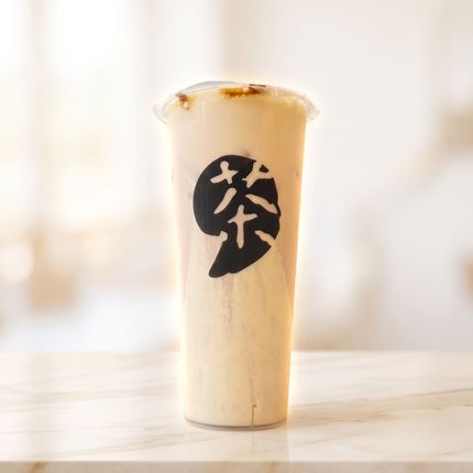 Tall creamy iced tea cup with a black logo on a bright background