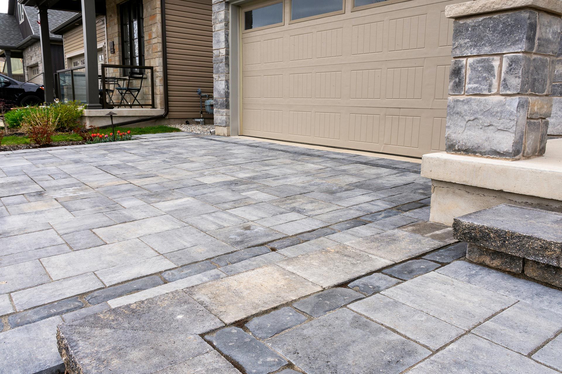 Stone driveway and beige garage door with stone steps at a house entrance
