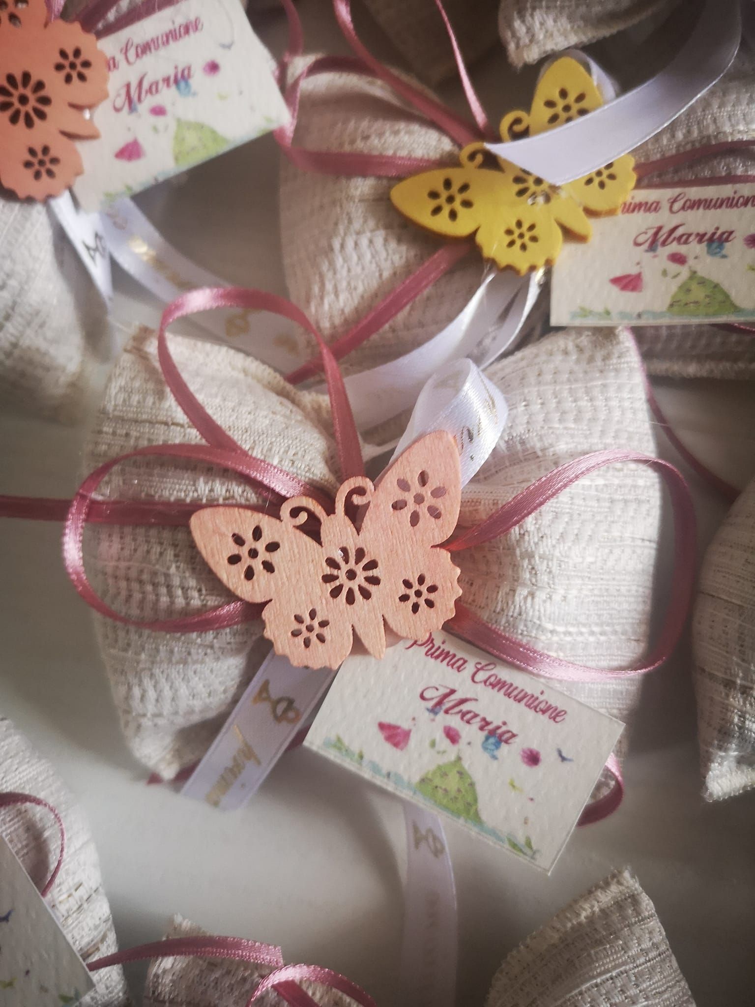 Piccoli sacchetti regalo in iuta, legati con nastri color malva e decorati con farfalle di legno, con etichette recanti la scritta