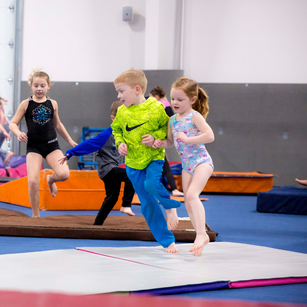 A boy in a neon green nike shirt is running on a mat