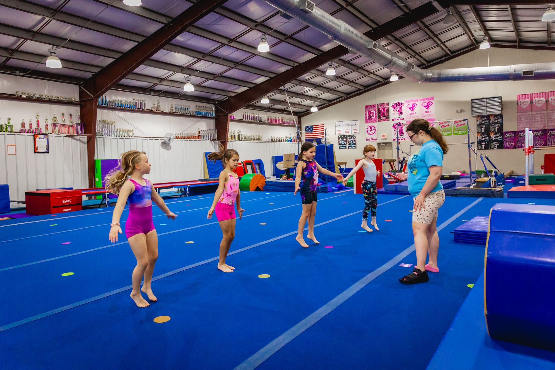 Gymnasts in an indoor gymnastics class warming up with jumps.