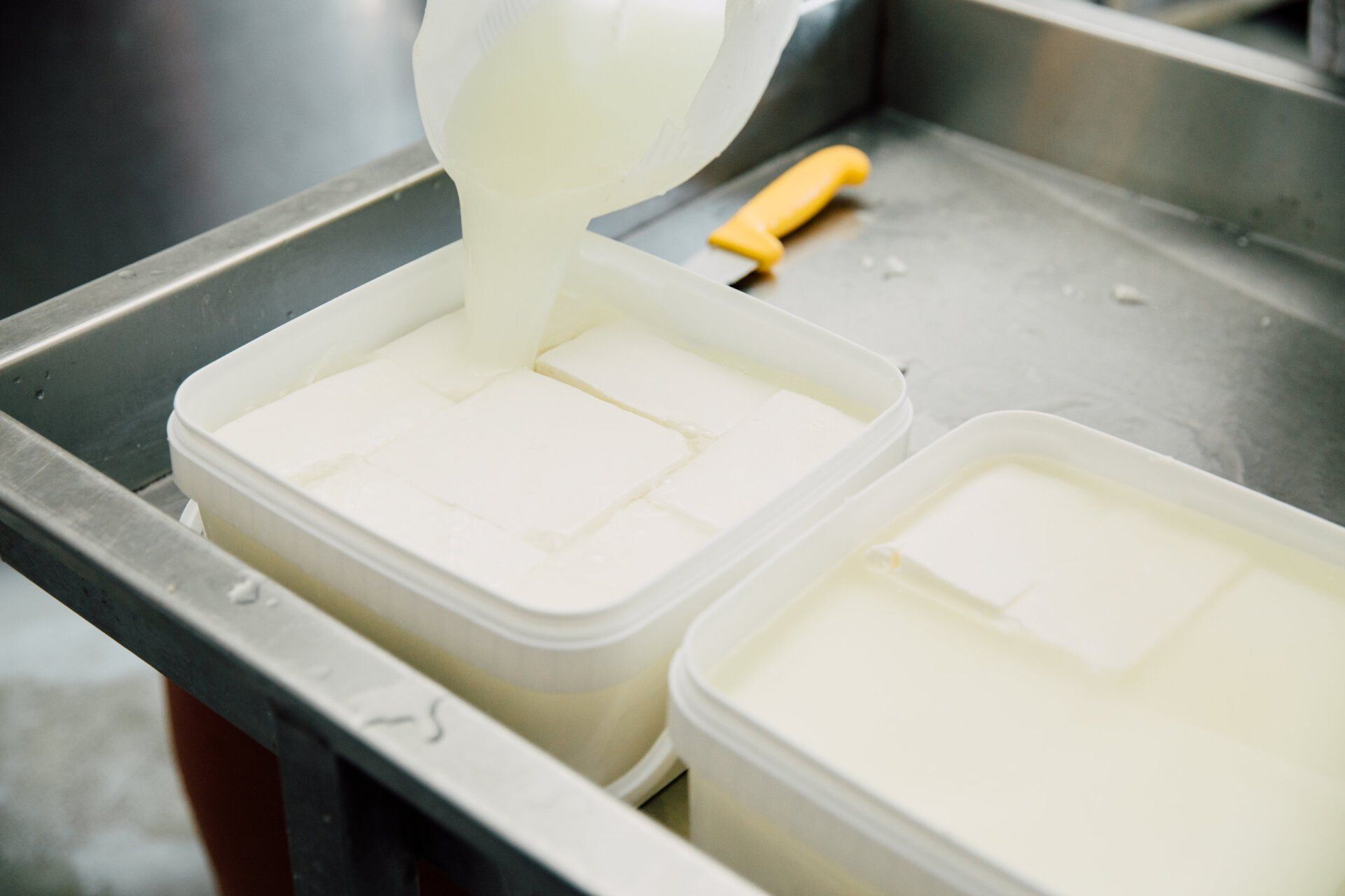 a person is pouring milk into a plastic container .