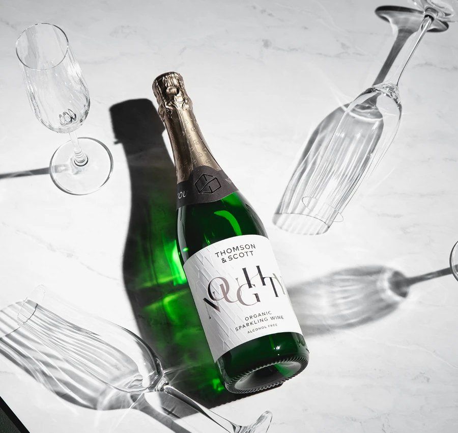 a bottle of champagne is surrounded by wine glasses on a table .