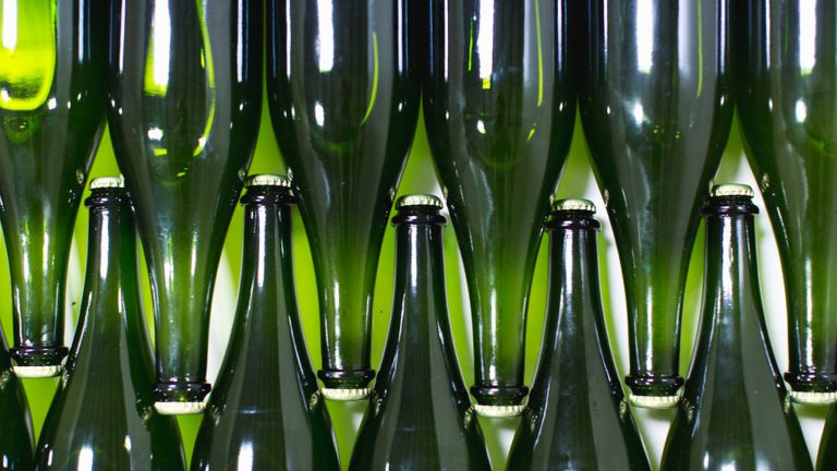 a row of green wine bottles are lined up in a row .