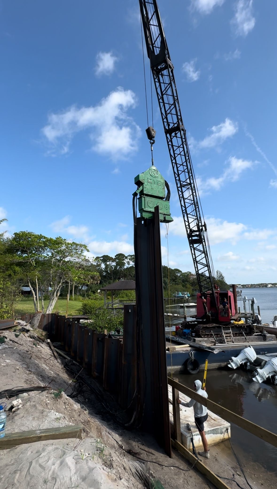 A crane is lifting a large piece of metal into the water.