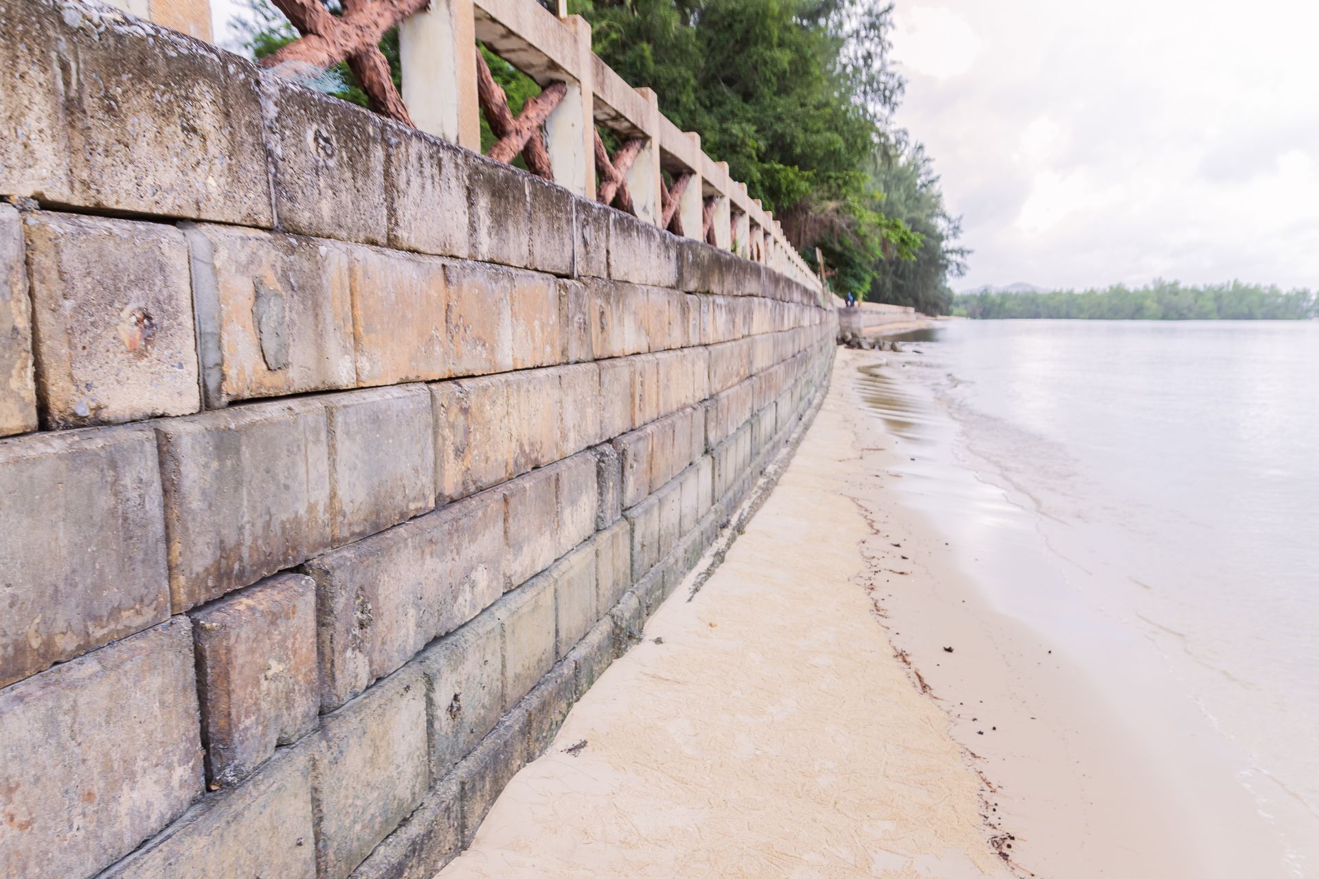 A brick wall along a beach next to a body of water.