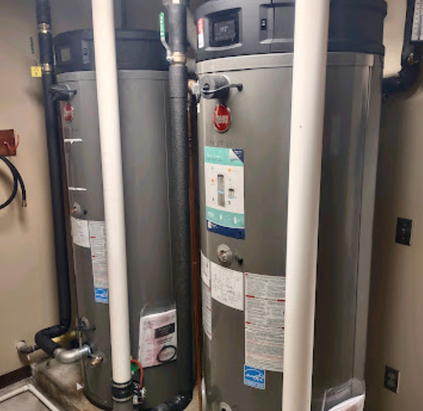 two water heaters are sitting next to each other in a room .