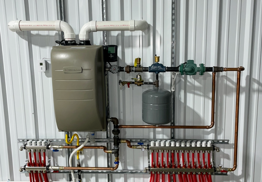 a boiler with a lot of pipes attached to it is hanging on a wall .