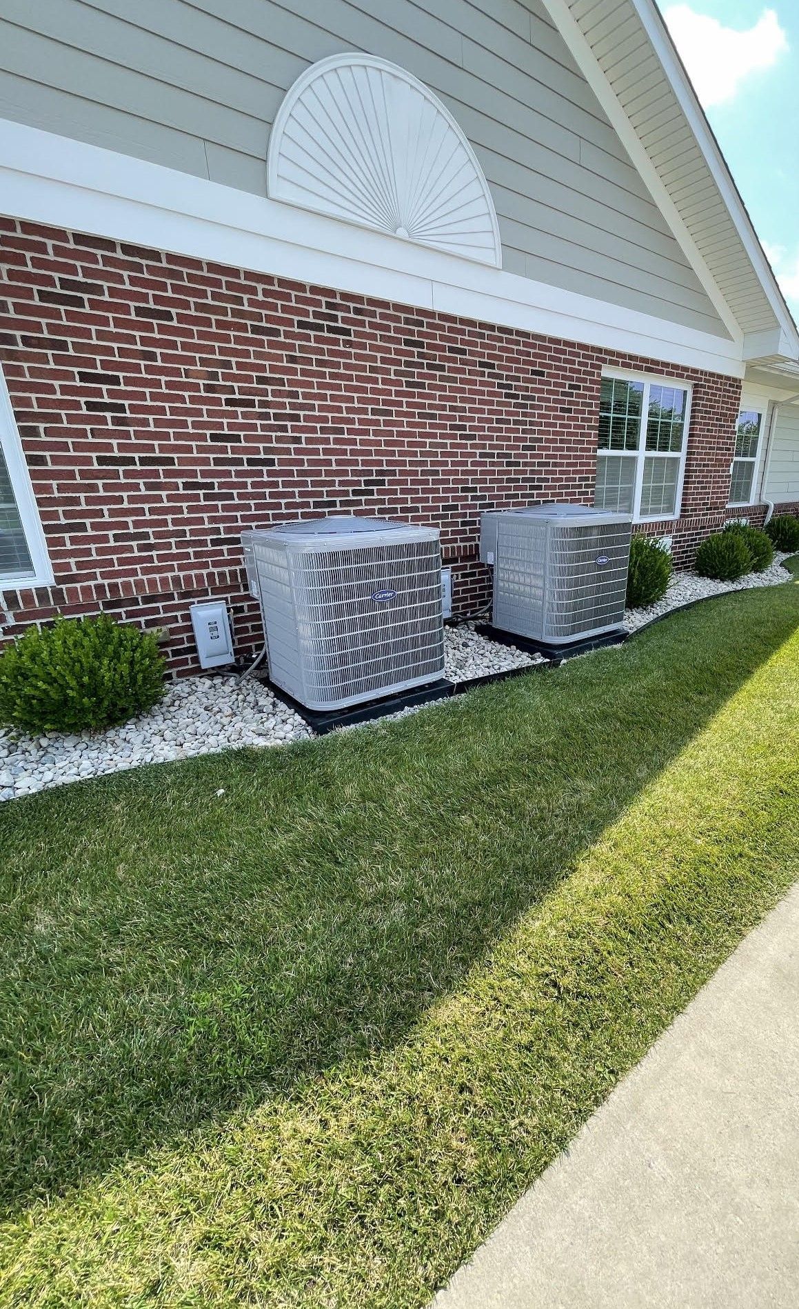 two air conditioners are sitting on the side of a brick house .