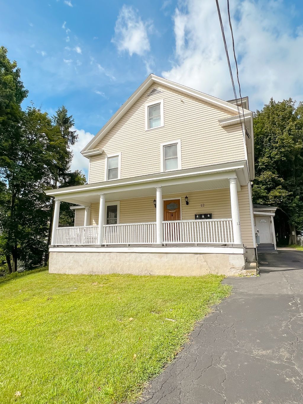 12 Calvert – Three-story cream-colored house with white columned front porch and paved driveway.