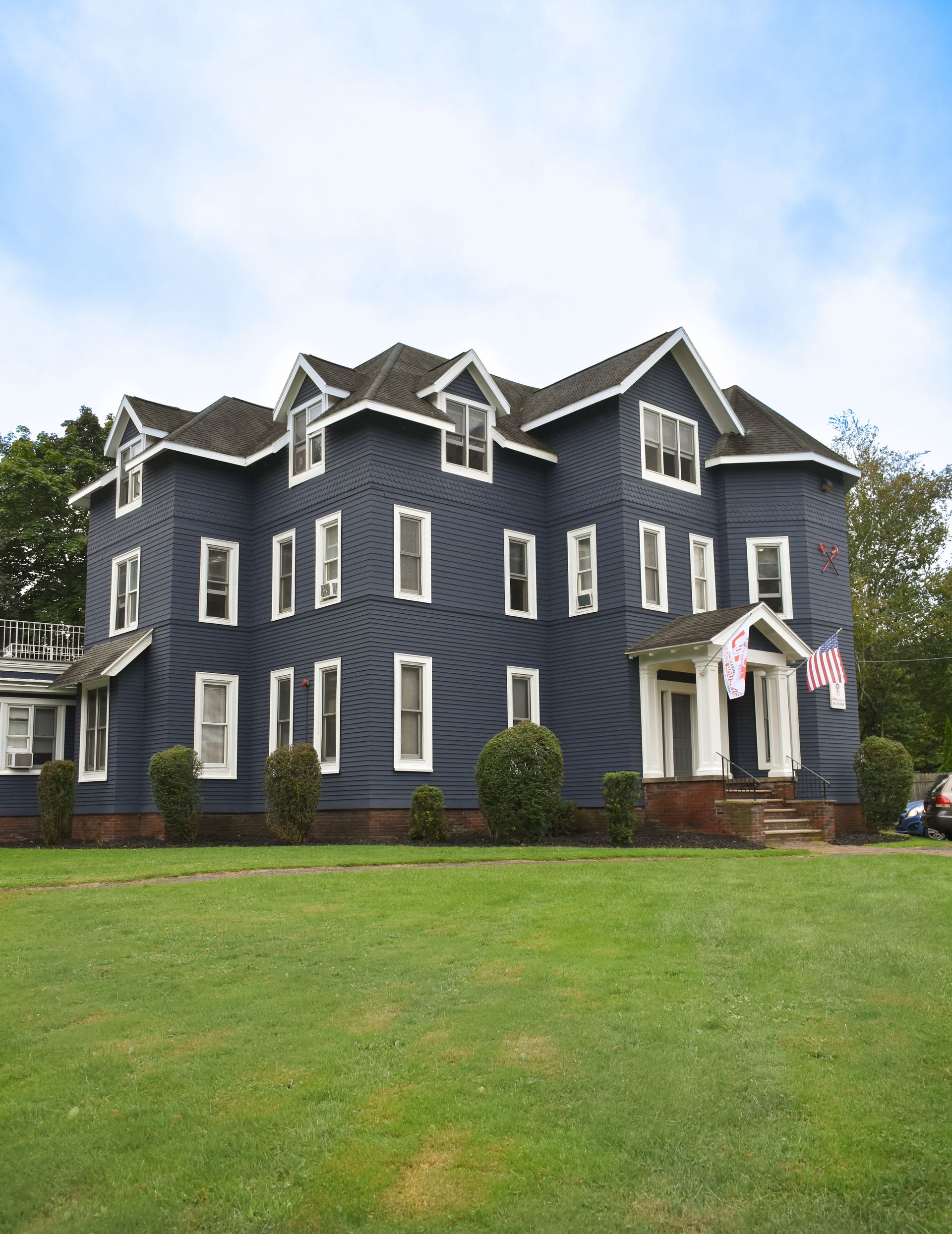 59 Tompkins – Large navy-blue multi-story house with white trim and American flags at the entrance.