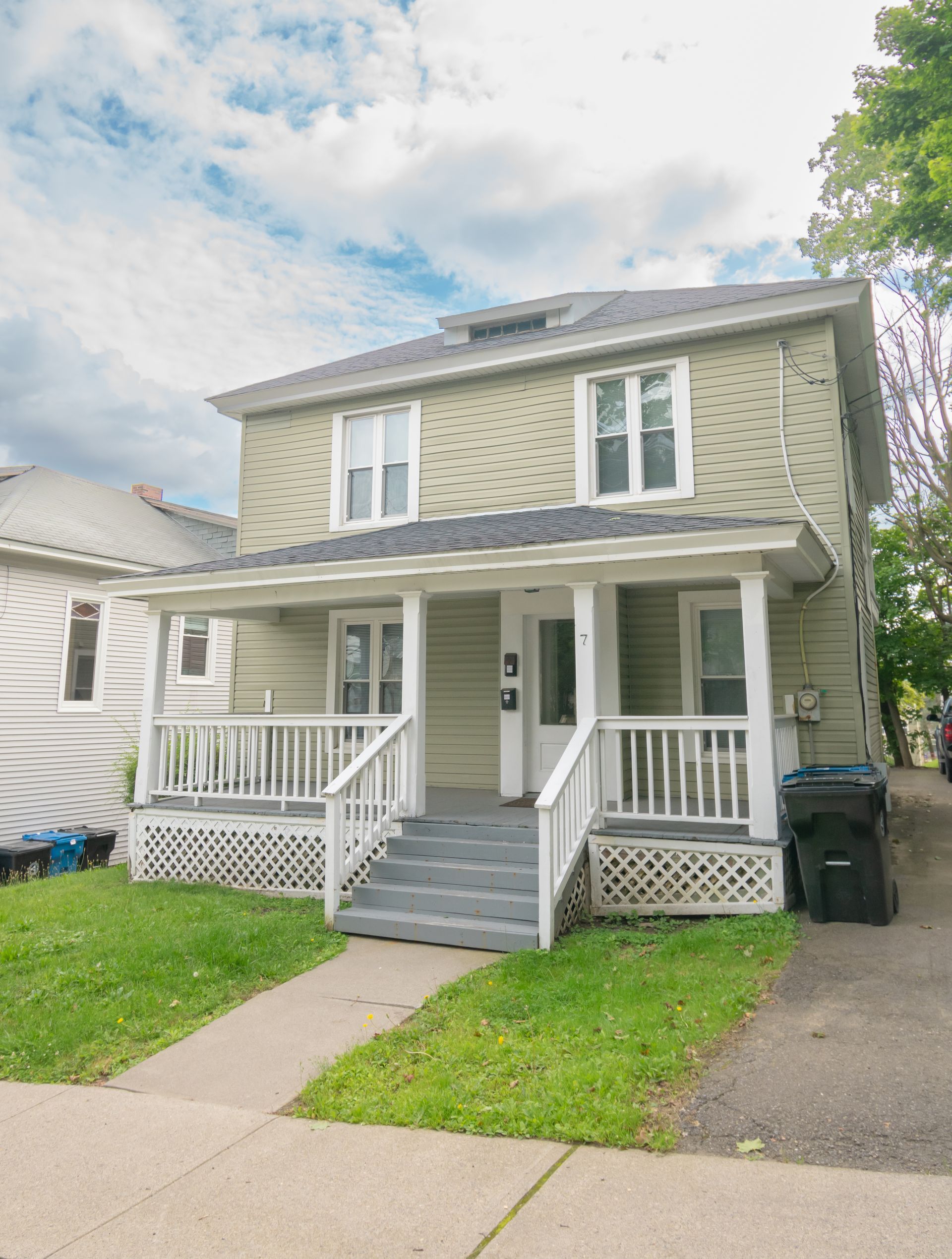 7 Pleasant – Beige two-story house with a covered front porch and lattice skirting.