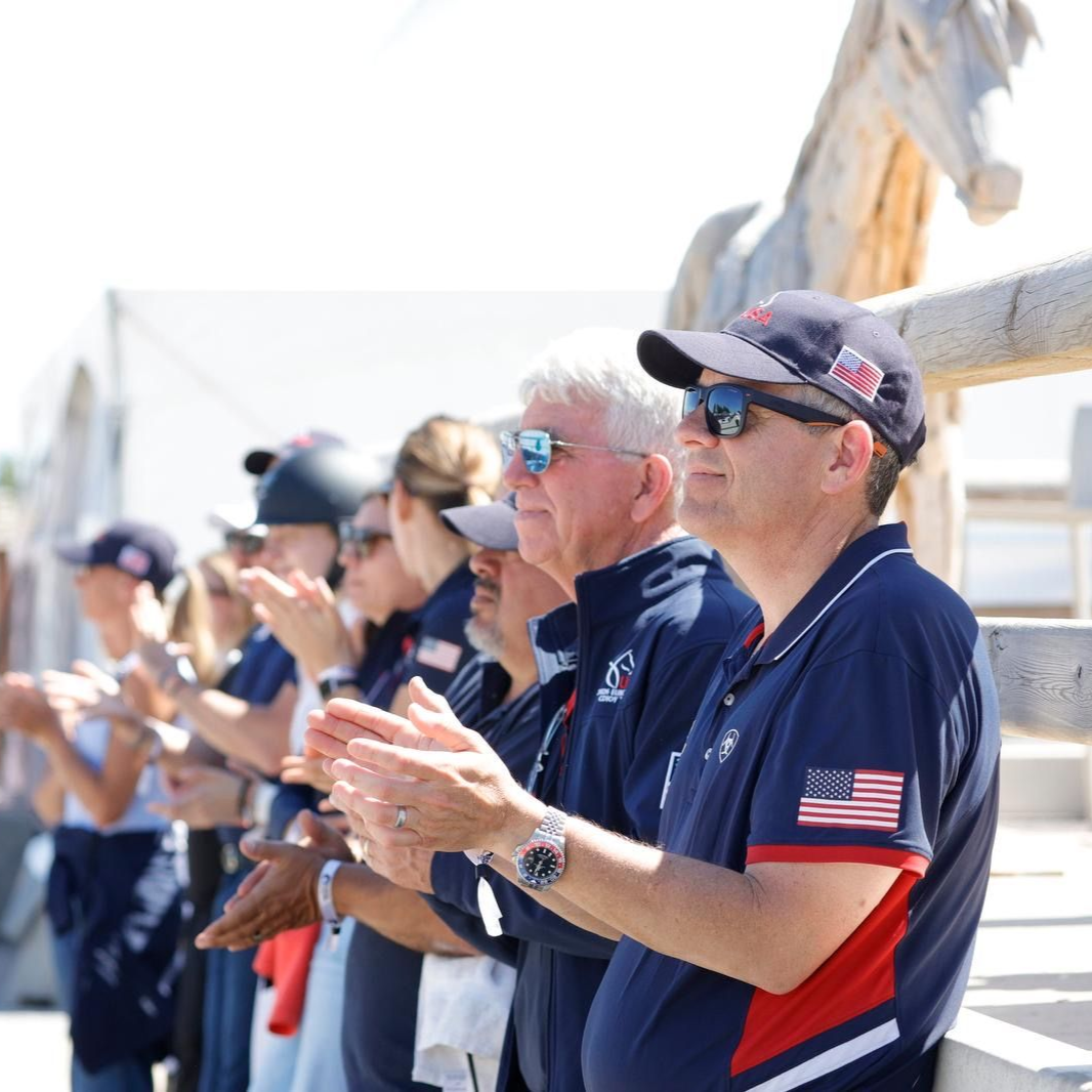 Dr Fred Nostrant USEF team veterinarian applauding rider performances with the rest of the team