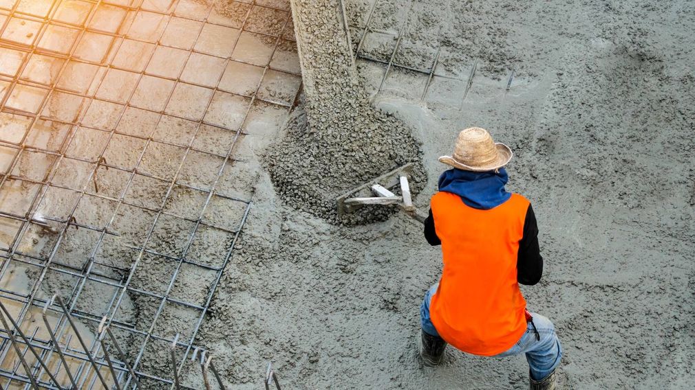 A construction worker is pouring concrete on a construction site.