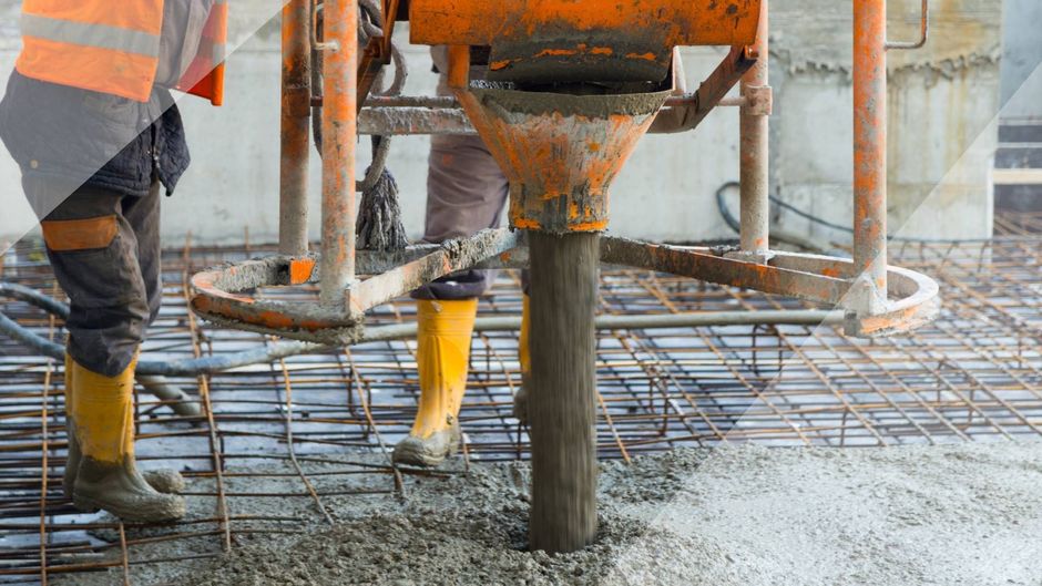A construction worker is pouring concrete on a construction site.