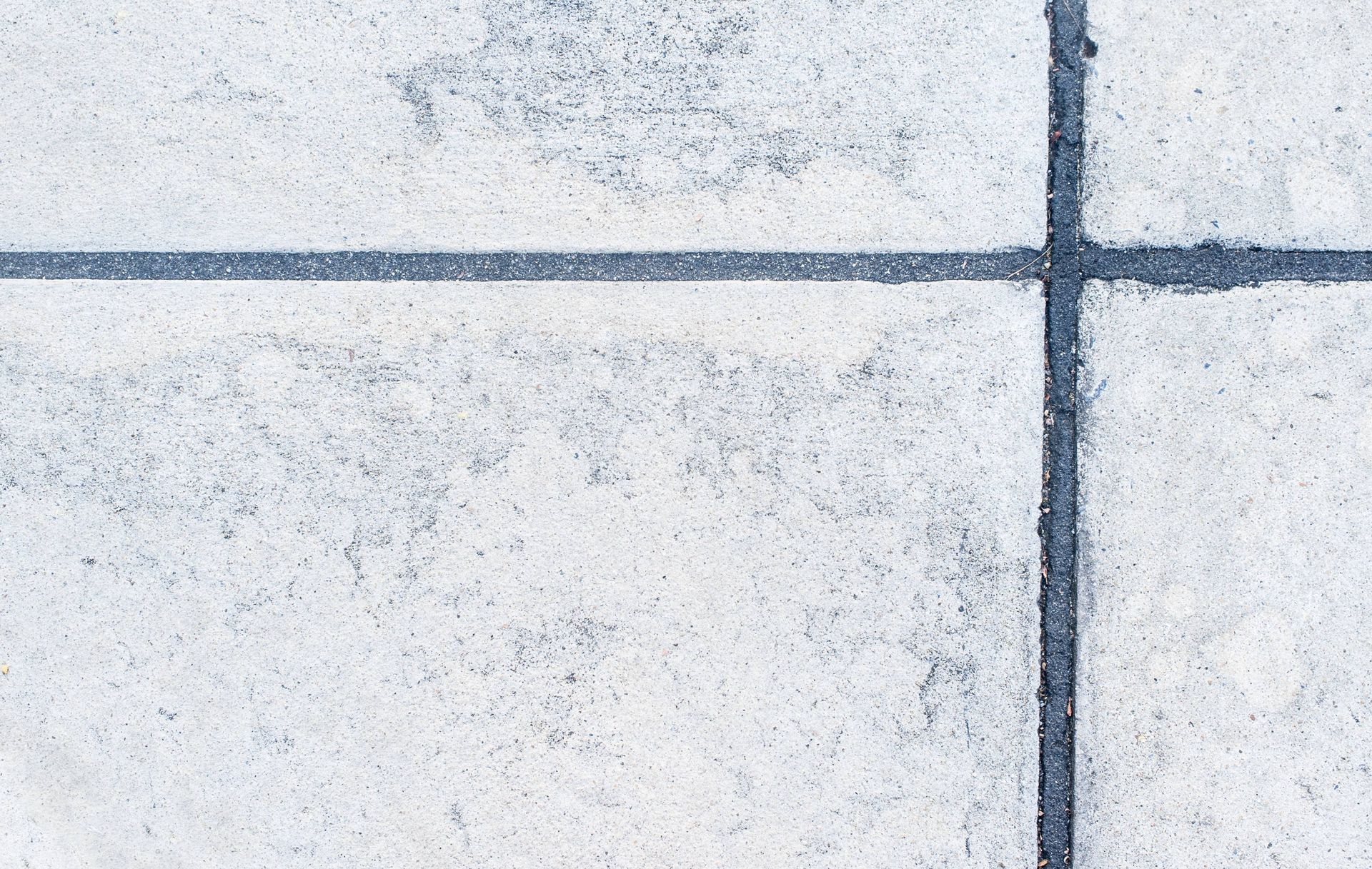 A close up of a concrete floor with a black line between the tiles.