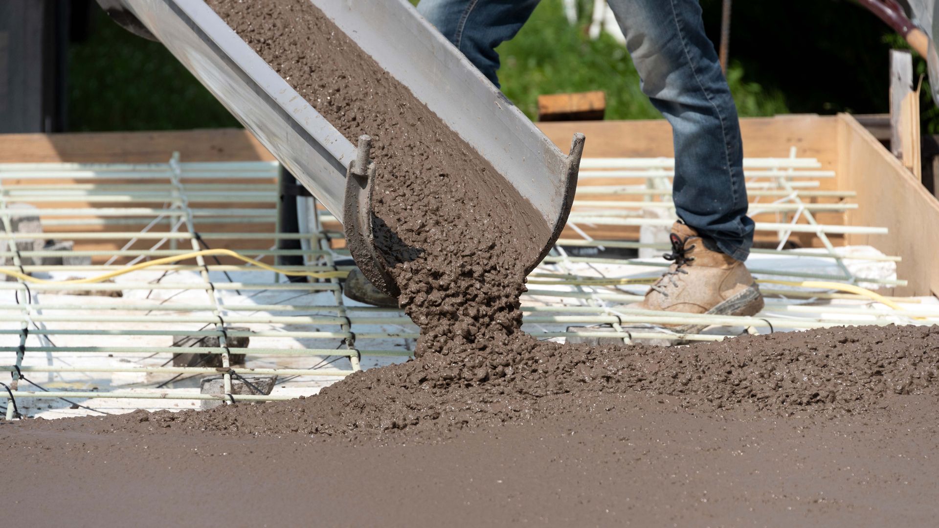 A man is pouring concrete into a concrete slab.