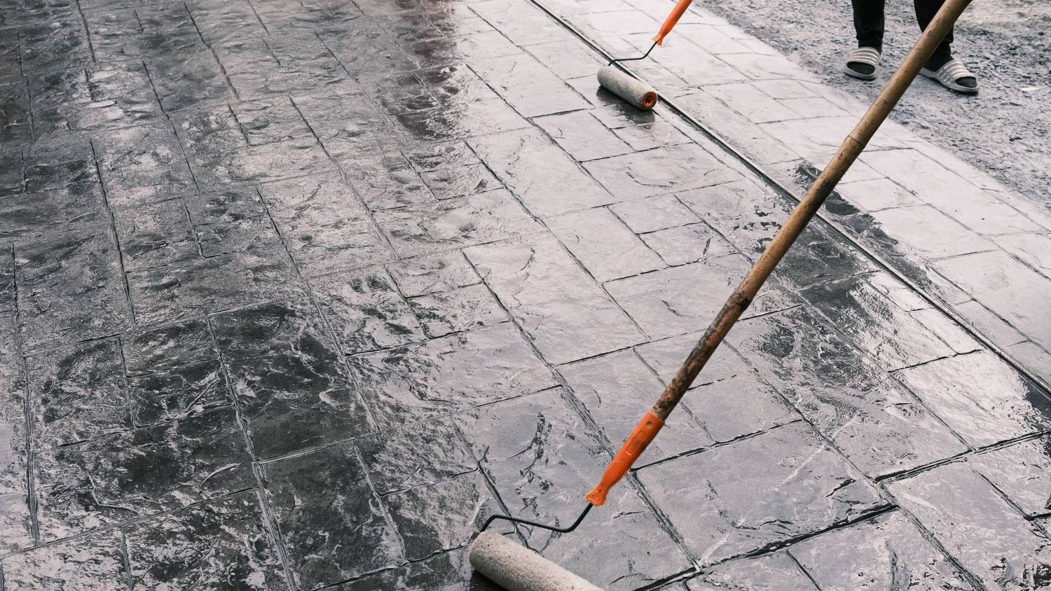 A person is painting a concrete floor with a roller.