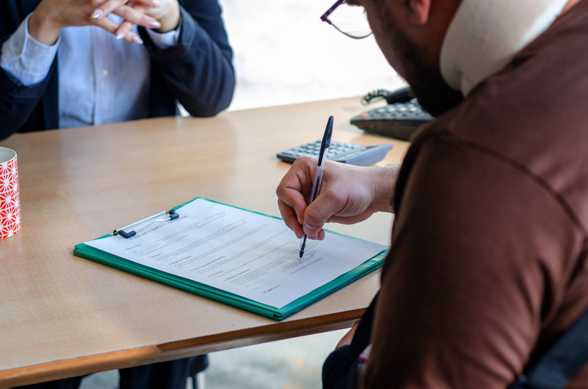 Man signing Social Security Disability paperwork with attorney present, consulting a Social Security