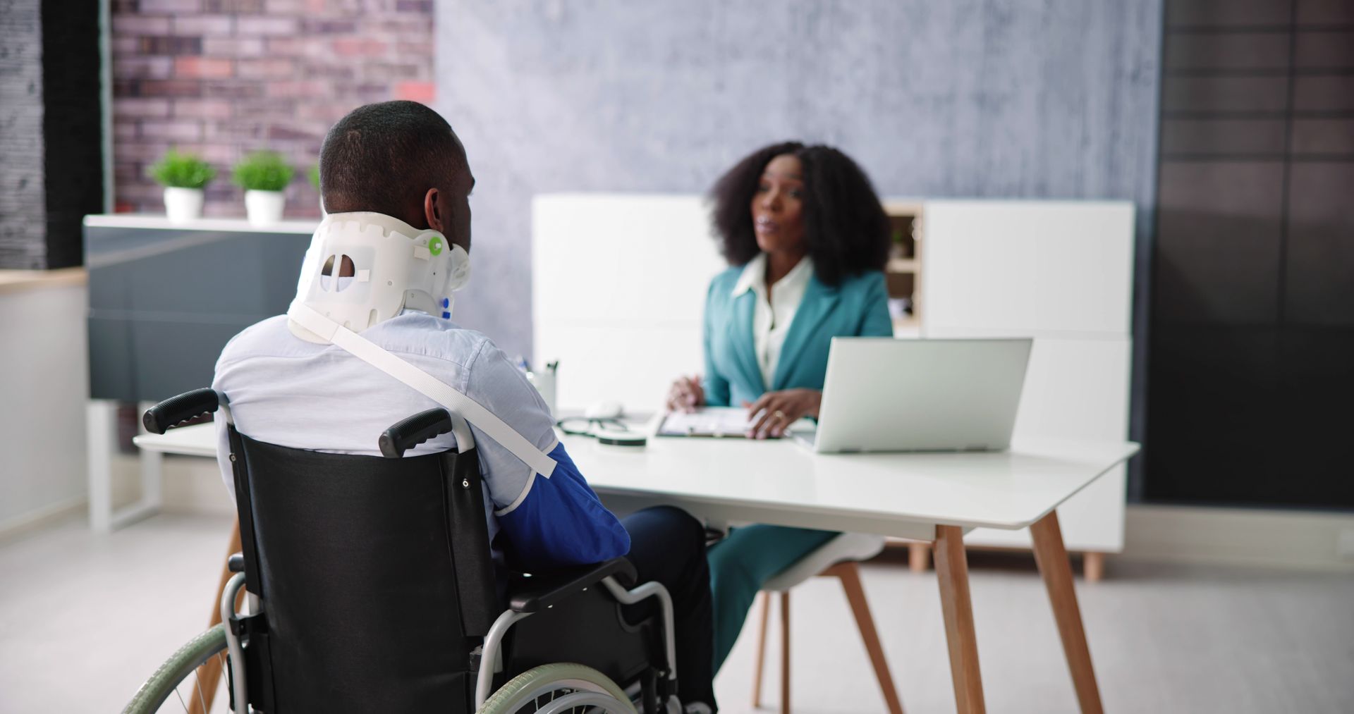 A Social Security Disability attorney consulting with a wheelchair client during an office appointment.