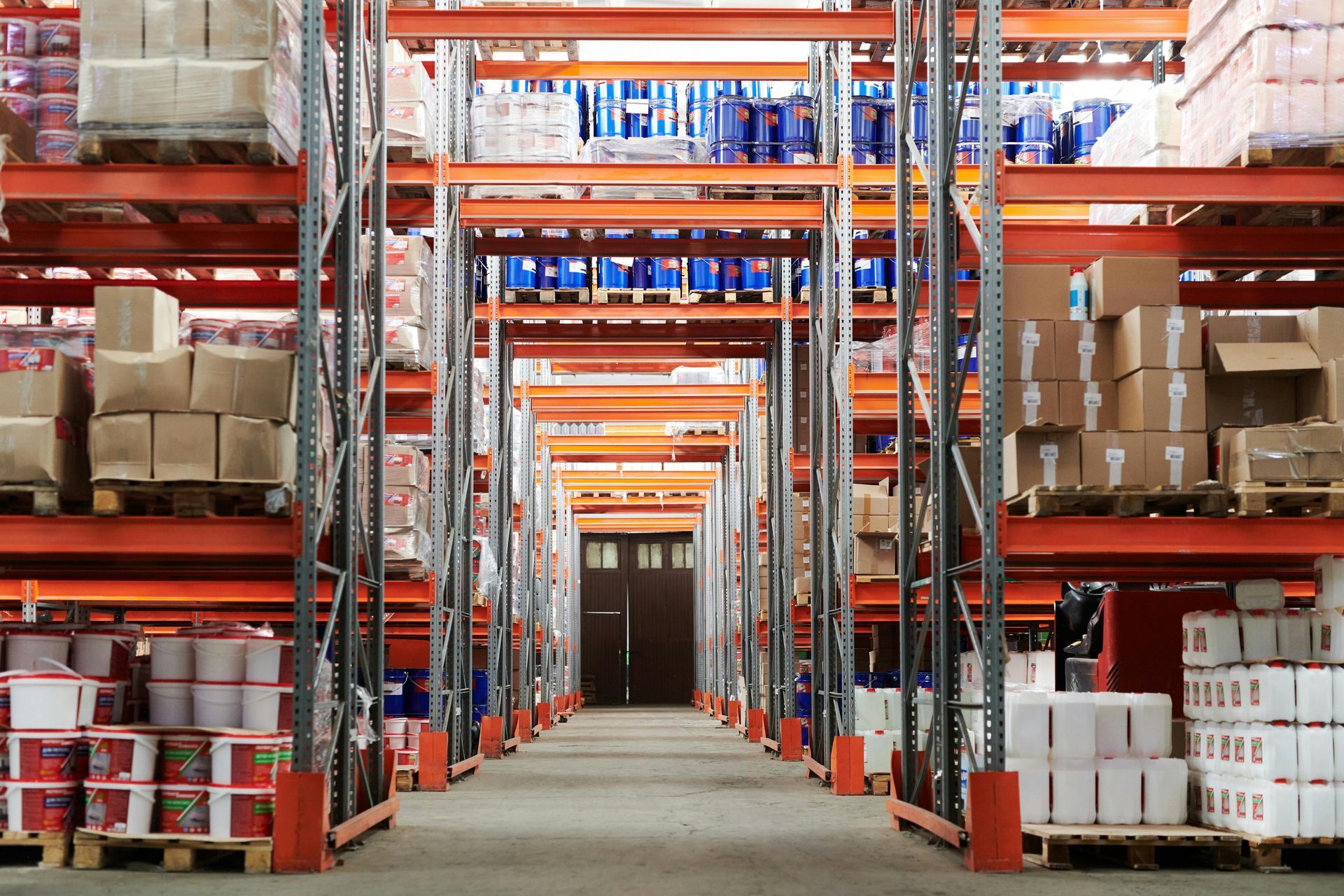 Warehouse interior with tall shelves stacked with boxes and containers.