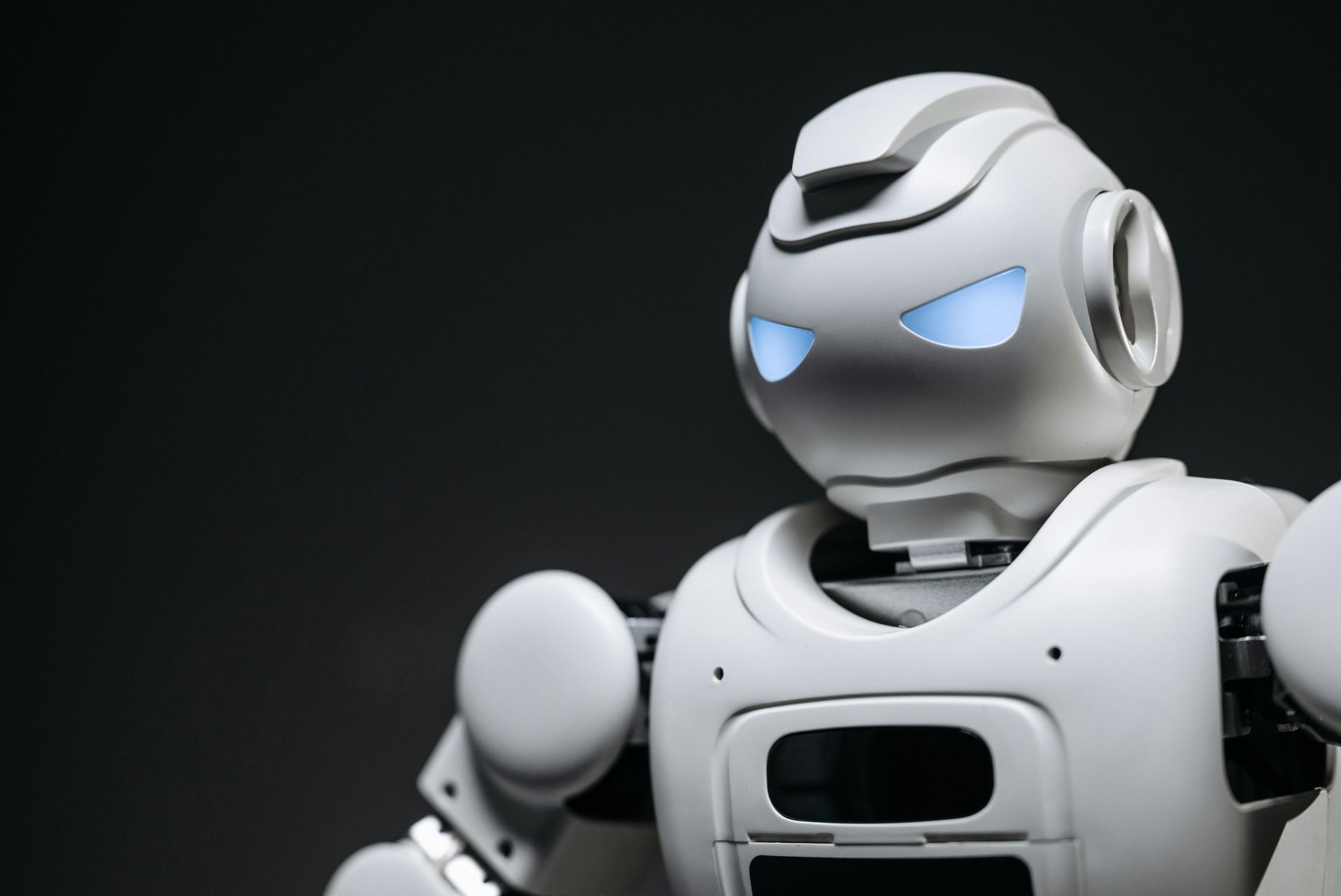 White robot with blue eyes against a dark background.