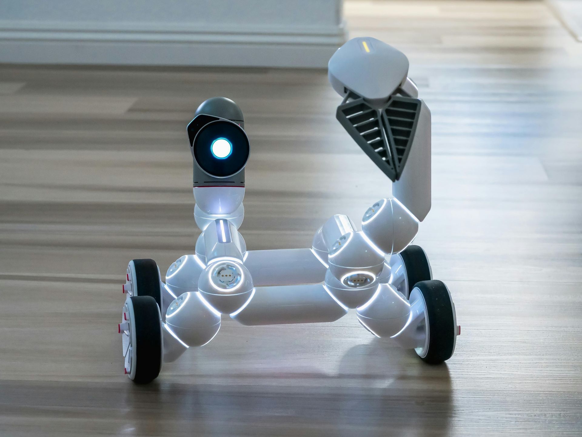 White robot with glowing lights on a wooden floor.