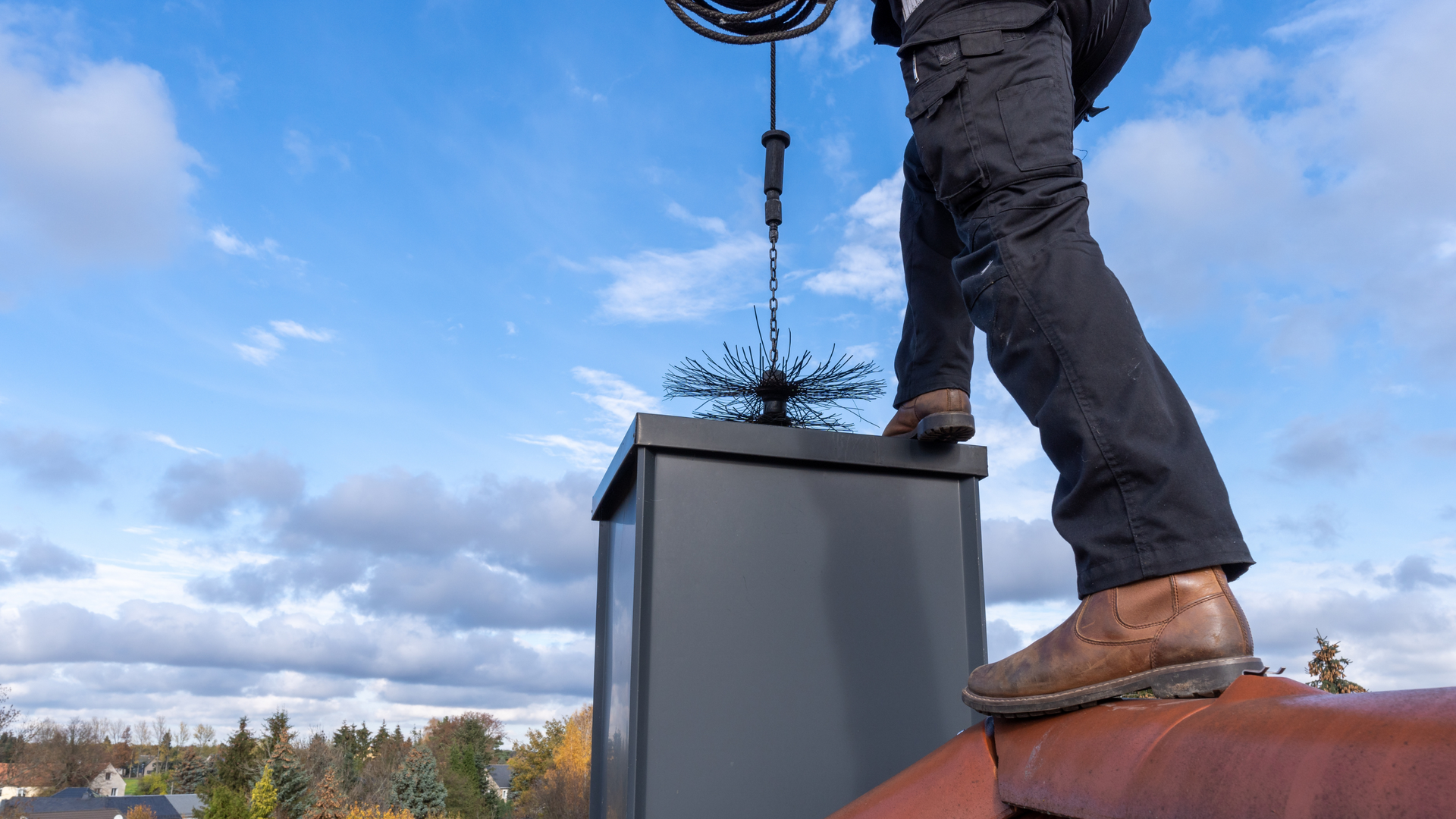 A man is standing on top of a chimney on a roof.