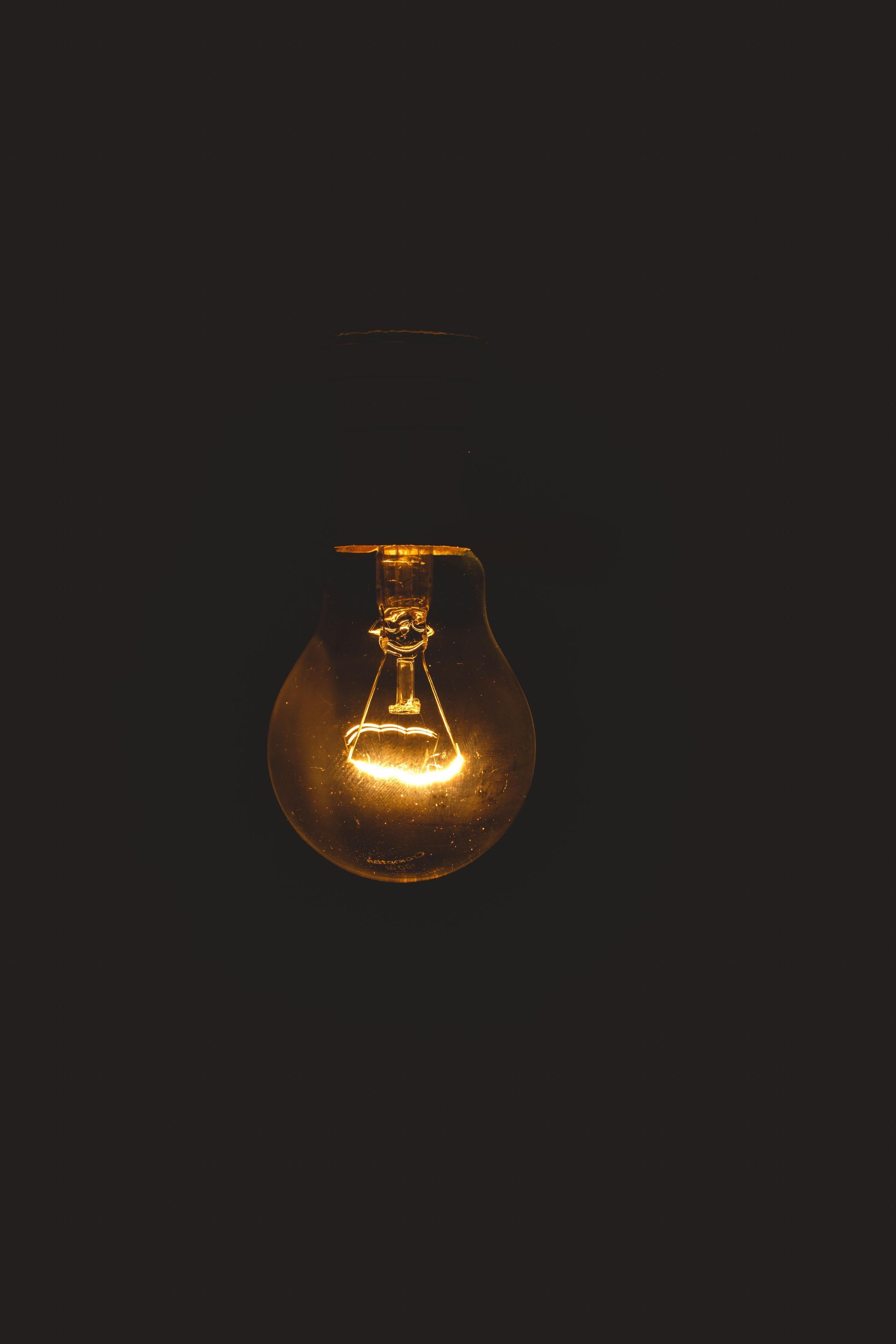Lit lightbulb glowing in a dark space.