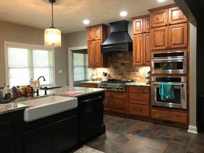 Kitchen with wood cabinets, black appliances, granite countertop, and island.