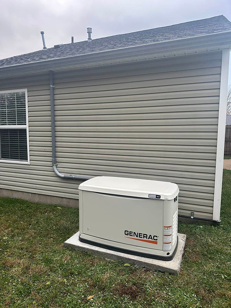 Generator installed outside a house with gray siding.