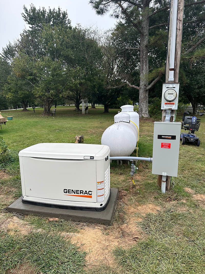 A Generac generator on a concrete pad with a propane tank, electrical meter, and panel in a yard.