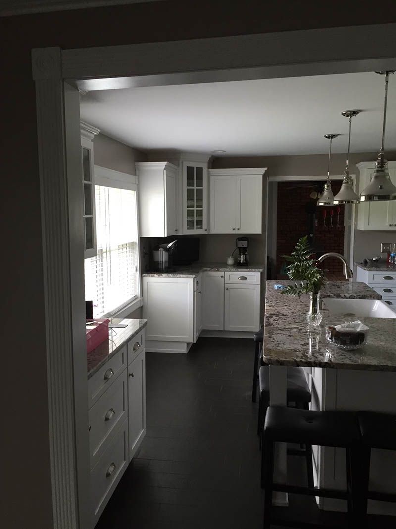 Kitchen with white cabinets, dark floors, and a granite island.