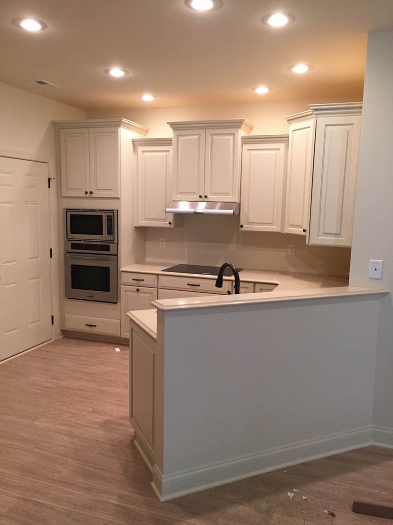Off-white kitchen with cabinets, built-in oven, cooktop, and a breakfast bar.