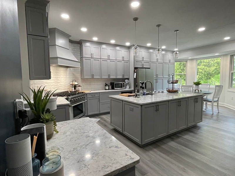 Gray kitchen with island, cabinets, appliances, and a dining area with a window and a table.