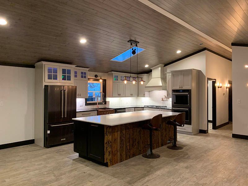 Modern kitchen with wood island, gray cabinets, stainless steel appliances, and a skylight.
