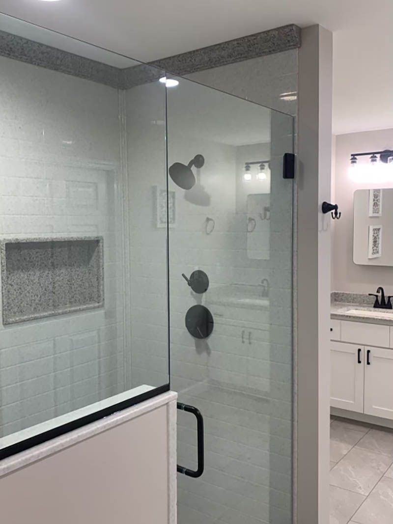 Modern bathroom with glass shower enclosure, black fixtures, and white tile.