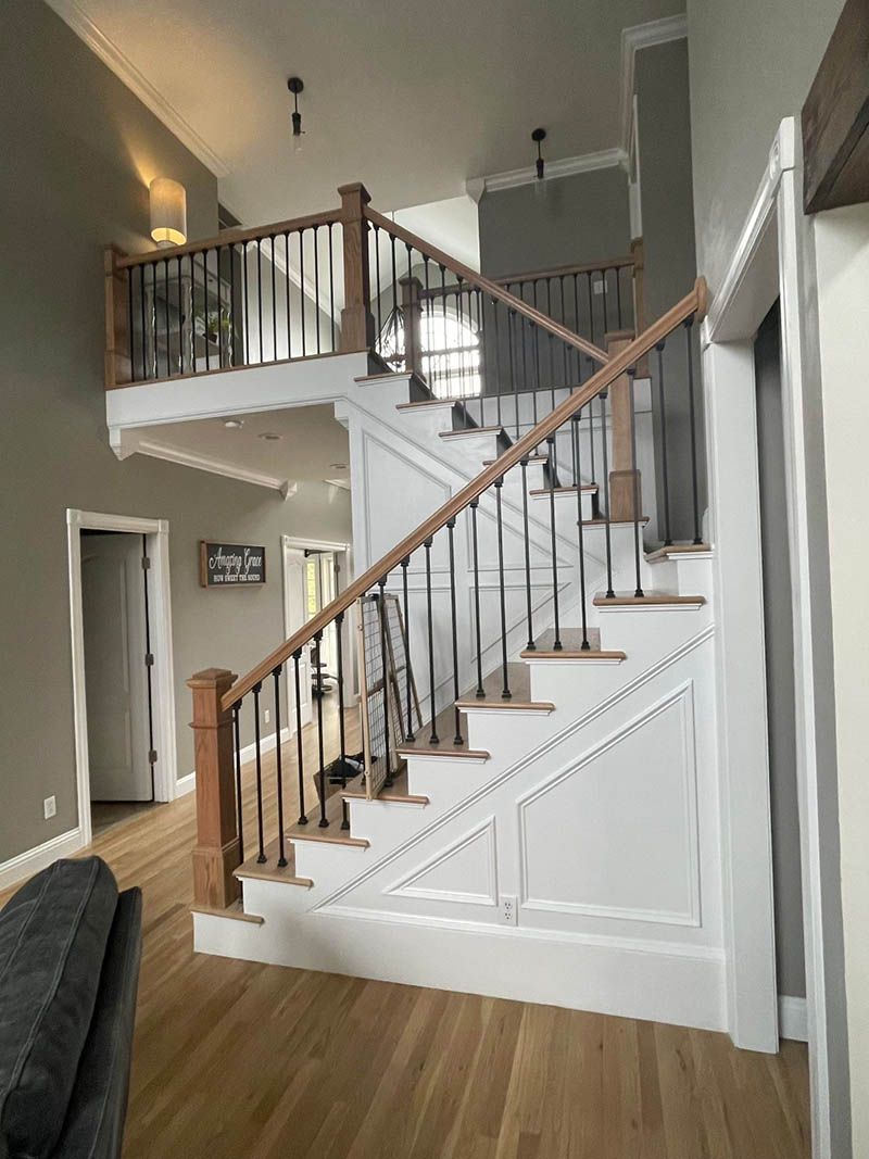Wooden staircase with black metal balusters and white accents. Hardwood flooring.