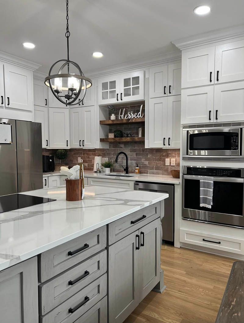White kitchen with island, stainless steel appliances, and brick backsplash.