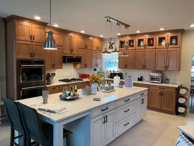 Spacious kitchen with wood cabinets, white island with black hardware, and stainless steel appliances.